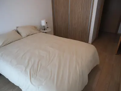 a bedroom with a white bed with a wooden floor at Rúa Mariñeiro in Burela de Cabo