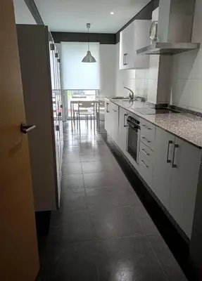 a kitchen with white cabinets and a table at Rúa Mariñeiro in Burela de Cabo