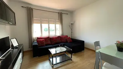 a living room with a black couch and a window at Apartamento céntrico in Burela de Cabo