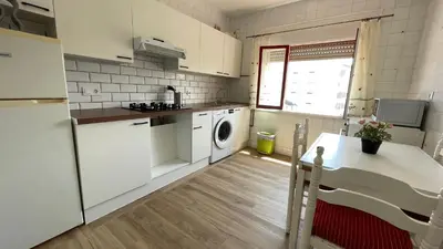 a kitchen with white appliances and a table in it at Apartamento céntrico in Burela de Cabo