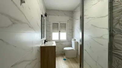 a white bathroom with a toilet and a window at Apartamento céntrico in Burela de Cabo