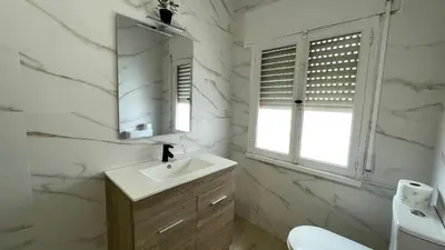 a white bathroom with a sink and a mirror at Apartamento céntrico in Burela de Cabo