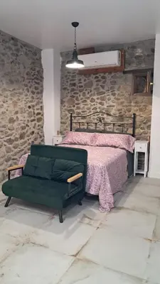 a bedroom with a bed and a stone wall at Casa Loma Lola in Molinaseca