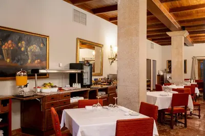 a restaurant with white tables and chairs and a kitchen at Parador de Verín in Monterrei