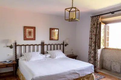 a bedroom with a bed with white sheets and a window at Parador de Verín in Monterrei