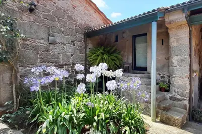 a garden with purple flowers in front of a brick building at Pension Do Picho