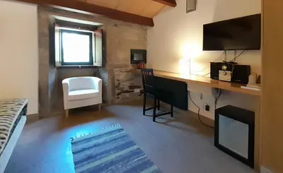 a room with a desk with a television and a chair at Pension Do Picho