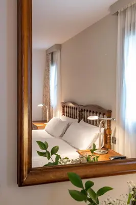 a mirror reflecting a bed in a bedroom at Parador de Villafranca del Bierzo in Villafranca del Bierzo