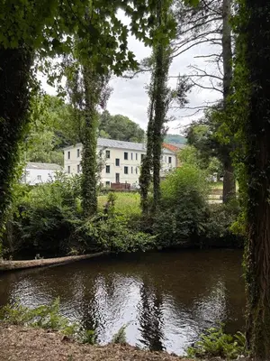 a river with a white building in the background at Hotel Casa dos Gardas in Samos