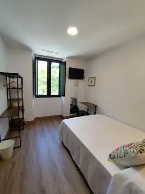 a bedroom with a large white bed and a desk at Hotel Casa dos Gardas in Samos