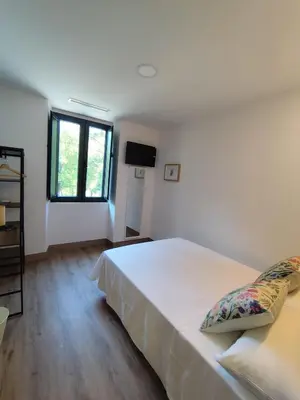 a bedroom with a large white bed and a television at Hotel Casa dos Gardas in Samos