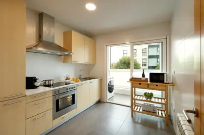 a kitchen with white cabinets and a large window at Vita Homes by Upper Luxury Housing in Santiago de Compostela