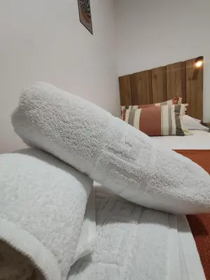 a pile of white towels sitting on a bed at Night Day in Padrón