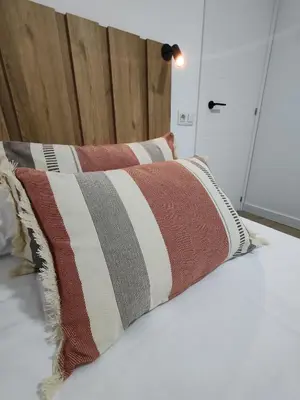 a pillow on a bed with a wooden headboard at Night Day in Padrón