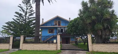 a blue house behind a fence with palm trees at Casa Julia in Barreiros