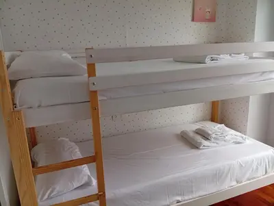 two bunk beds in a room with white sheets at Fonteculler centro in Culleredo