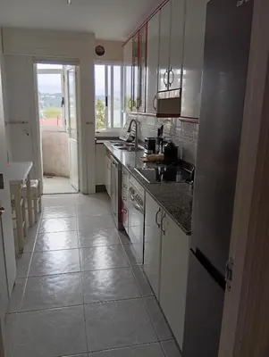 a kitchen with white cabinets and a tile floor at Fonteculler centro in Culleredo
