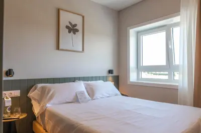 a bedroom with a white bed with a window at SNÖ Porta das Fragas in A Capela
