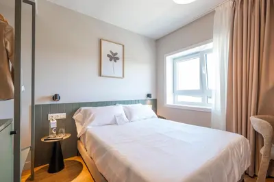 a bedroom with a white bed and a window at SNÖ Porta das Fragas in A Capela