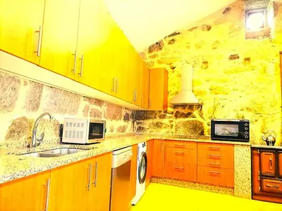 a kitchen with yellow cabinets and a sink at La Casa del Bosque del Agua y SPA Prexigueiro Obsequio entrada por persona a circuito termal in Mondariz