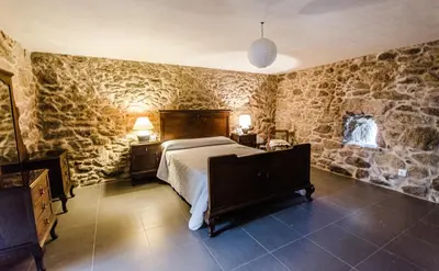 a bedroom with a bed and a stone wall at Casa Vaz in A Estrada
