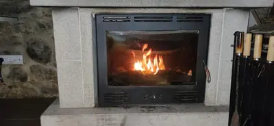 a stone fireplace with a fire in it at Casa Vaz in A Estrada
