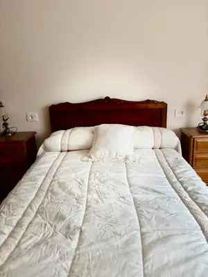 a bedroom with a white bed with a wooden headboard at Aloe Cela in Outeiro de Rei