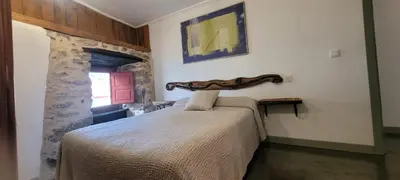a bedroom with a bed and a stone wall at Casa Otero in Serode