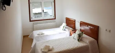 a room with two beds and a window at Pension El Caminante in Portomarin