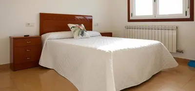a bedroom with a large white bed with a wooden headboard at Pension El Caminante in Portomarin