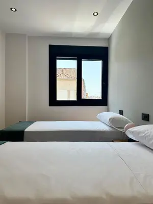 two beds in a room with a window at Lemos Lar in Monforte de Lemos