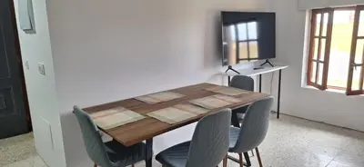a dining room table with chairs and a television at Casa Julia, primera línea de playa junto a las Catedrales in San Miguel Reinante