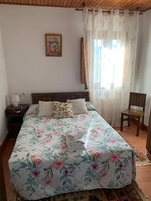 a bedroom with a bed with a floral bedspread at Casa do Carpinteiro in Crecíente
