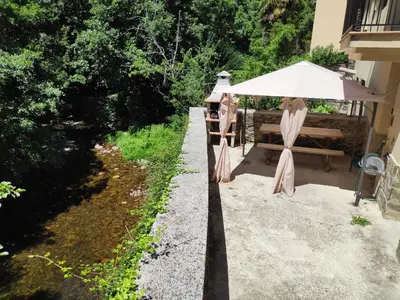 a table with an umbrella and a bench at Apartamentos el Rincon de Limes in Cangas del Narcea