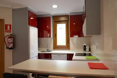 a kitchen with red cabinets and a counter top at Apartamentos el Rincon de Limes in Cangas del Narcea
