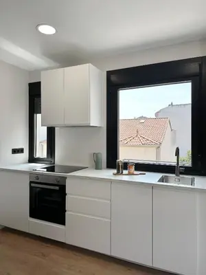 a kitchen with white cabinets and a large window at Lemos Agra in Monforte de Lemos