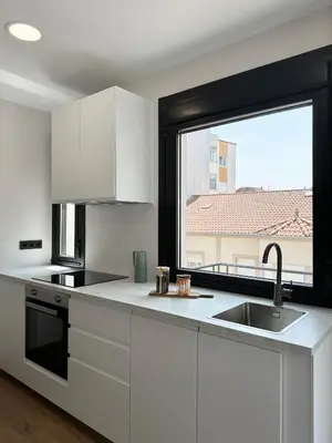 a kitchen with white cabinets and a large window at Lemos Agra in Monforte de Lemos