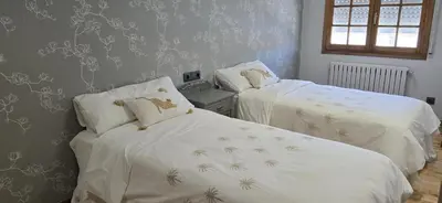 a bedroom with two beds with white sheets and wallpaper at Maruja Rural 2 in Sober