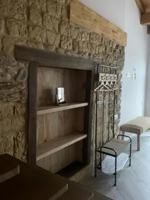 a room with a stone wall with shelves and a chair at La Higuera in Cacabelos
