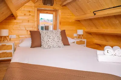 a bed in a log cabin with two lamps at Cabañas de Allariz - Cabaña 5 in Allariz