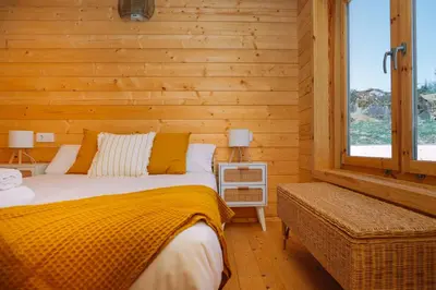 a bed in a room with a wooden wall at Cabañas de Allariz in Allariz