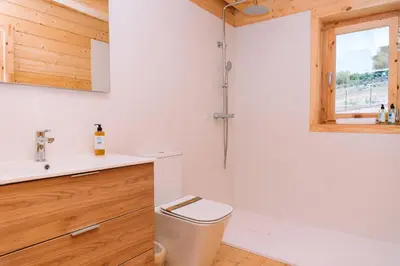 a bathroom with a toilet and a sink and a window at Cabañas de Allariz in Allariz