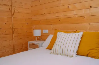a bedroom with a bed with a wooden wall at Cabañas de Allariz - Cabaña 4 in Allariz