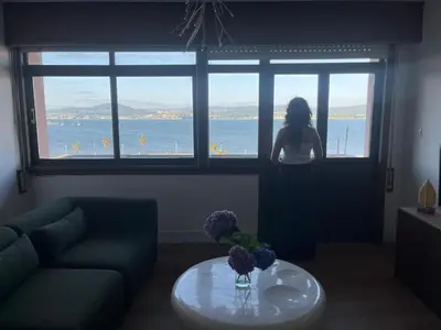 a woman looking out of a window at the water at cospeito in Sada