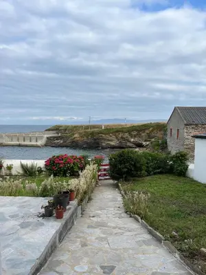 a walkway with flowers and a house and the ocean at Casa costa de Lugo frente al mar in Nois
