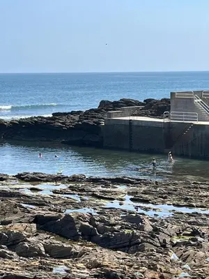 people swimming in the water on a rocky beach at Casa costa de Lugo frente al mar in Nois