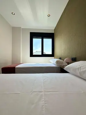 two beds in a room with a window at Lemos Nai in Monforte de Lemos