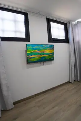 a white room with two windows and a flat screen tv at Chuspombo Apartamentos in Baralla