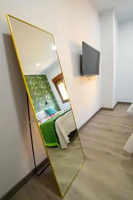 a mirror in a room with a bed and a tv at Chuspombo Apartamentos in Baralla