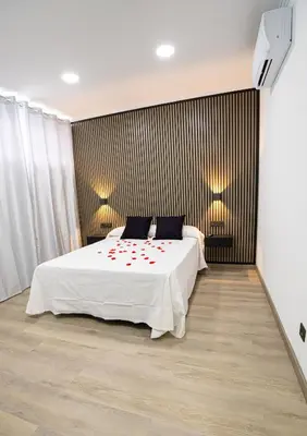 a bedroom with a white bed with red flowers on it at Chuspombo Apartamentos in Baralla